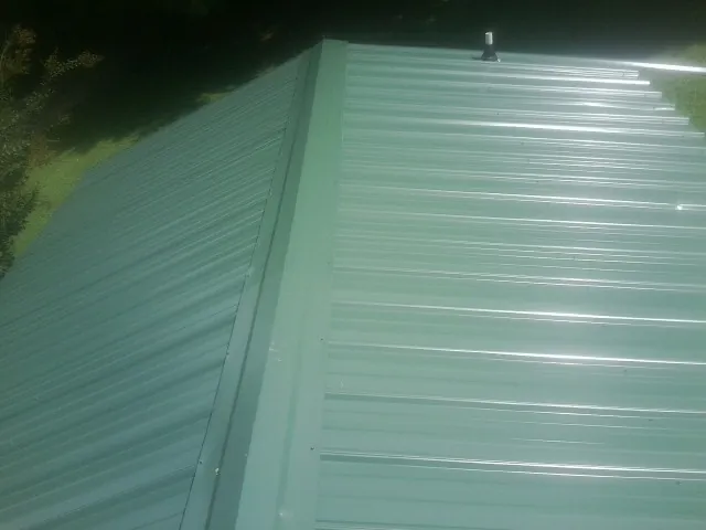 New green metal panels meeting at the ridge of a roof — Flat Roof Repair work by our crew in Ettrick