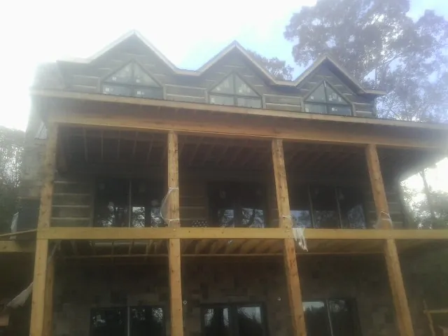Dormers and porch framing on a large log home under construction — Roof Coating work by our crew in Ettrick