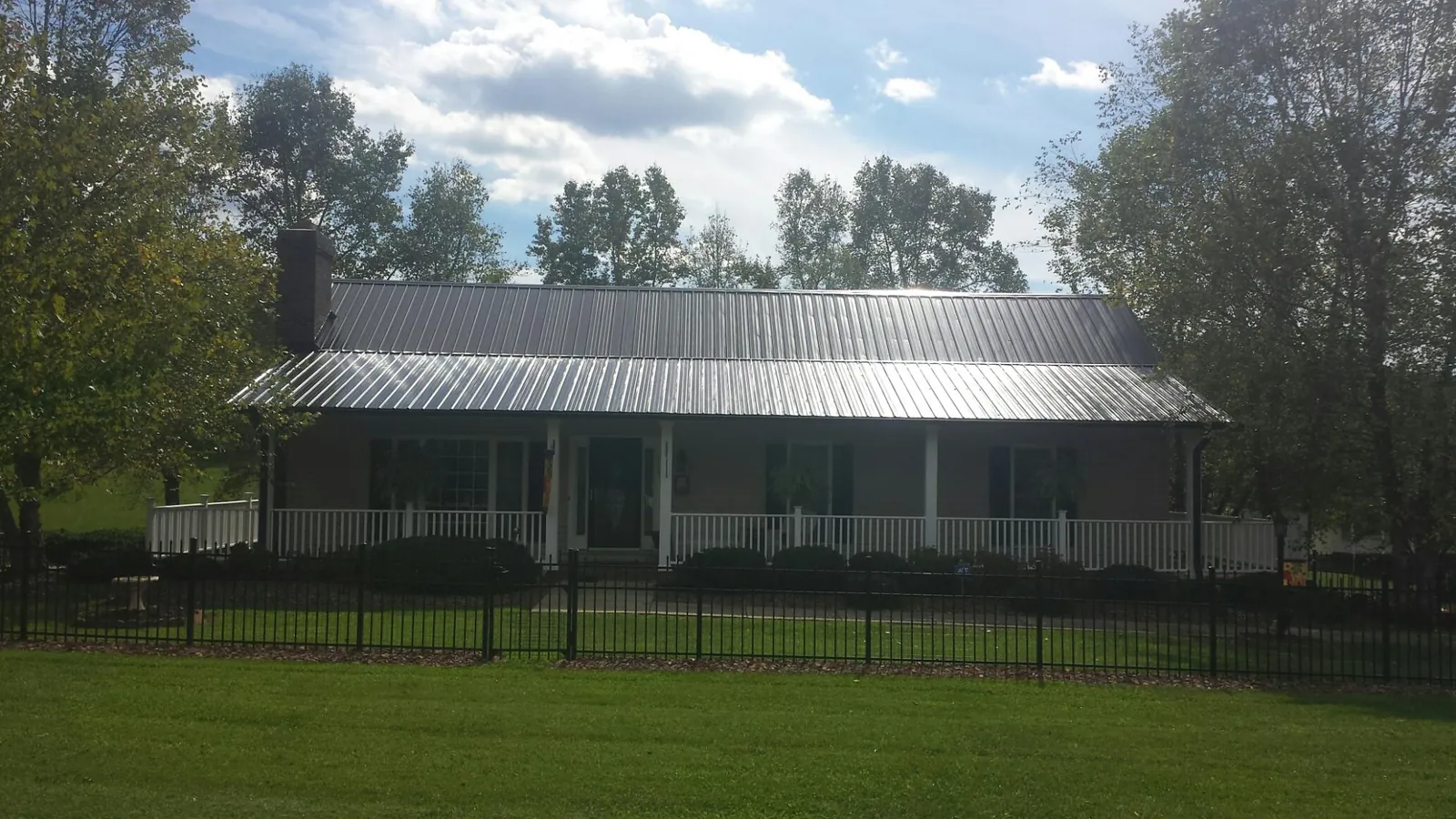 Gray metal roof on a brick ranch with a full width front porch — Gutter Guard Installation work by our crew in Ettrick