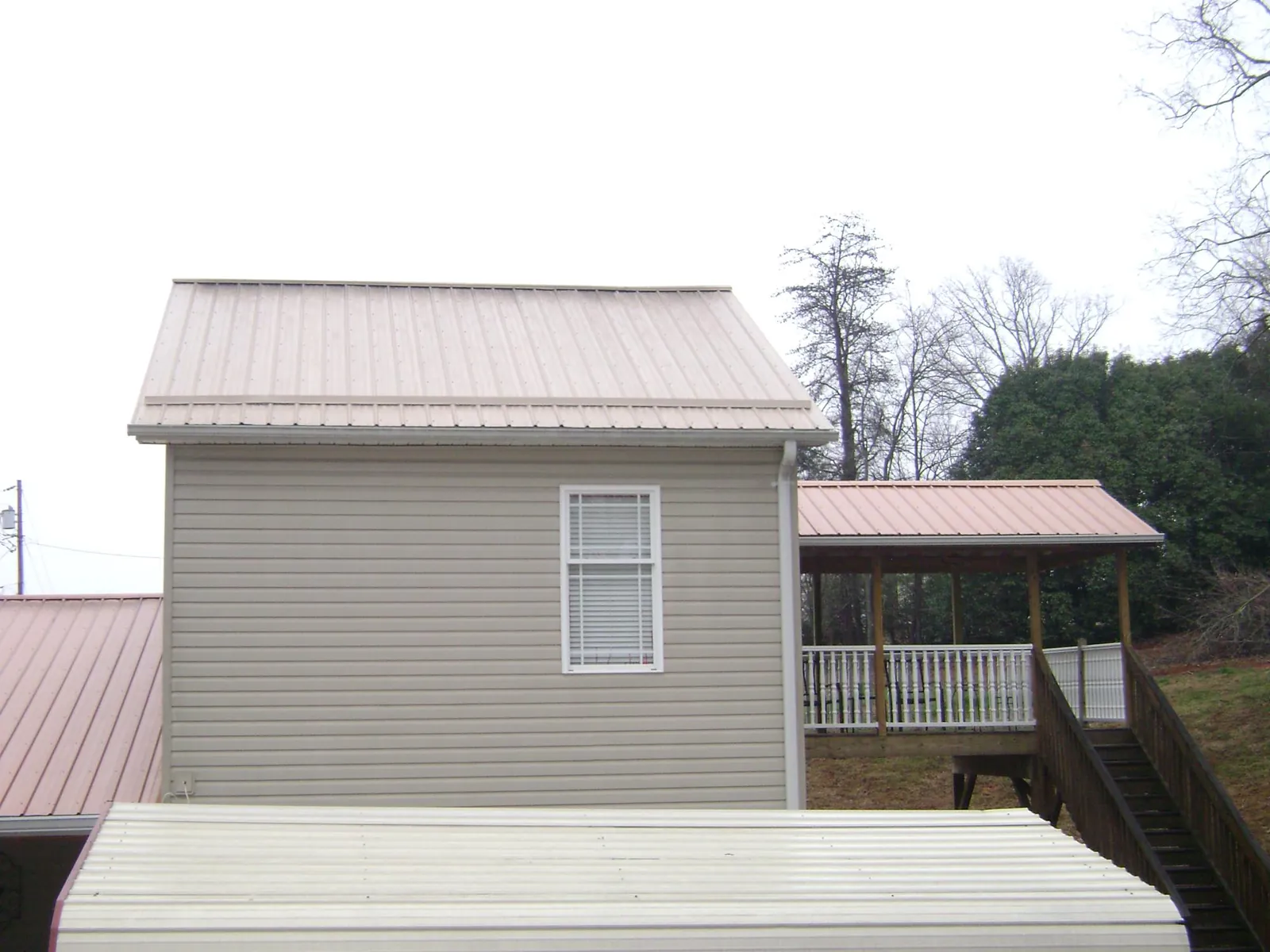 Tan metal roofs on a two story addition and attached porch, from a Roof Replacement job in Ettrick